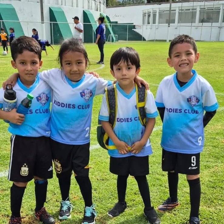 Cuatro jugadores de Kiddies Club sonriendo abrazados en la cancha