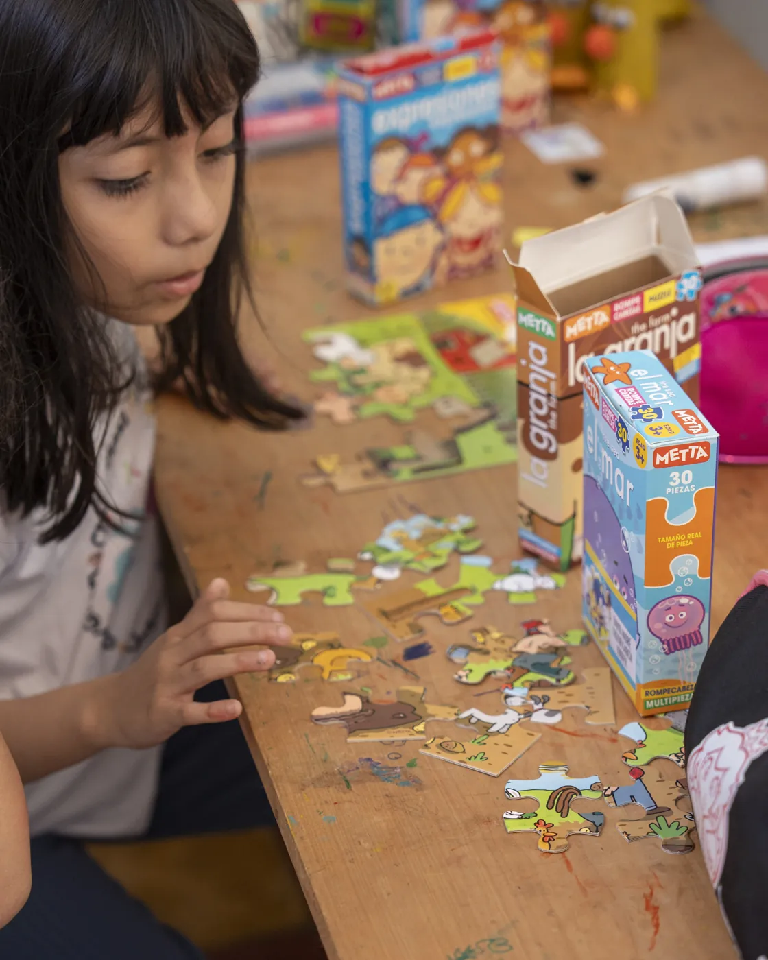 Niña concentrada armando un rompecabezas educativo